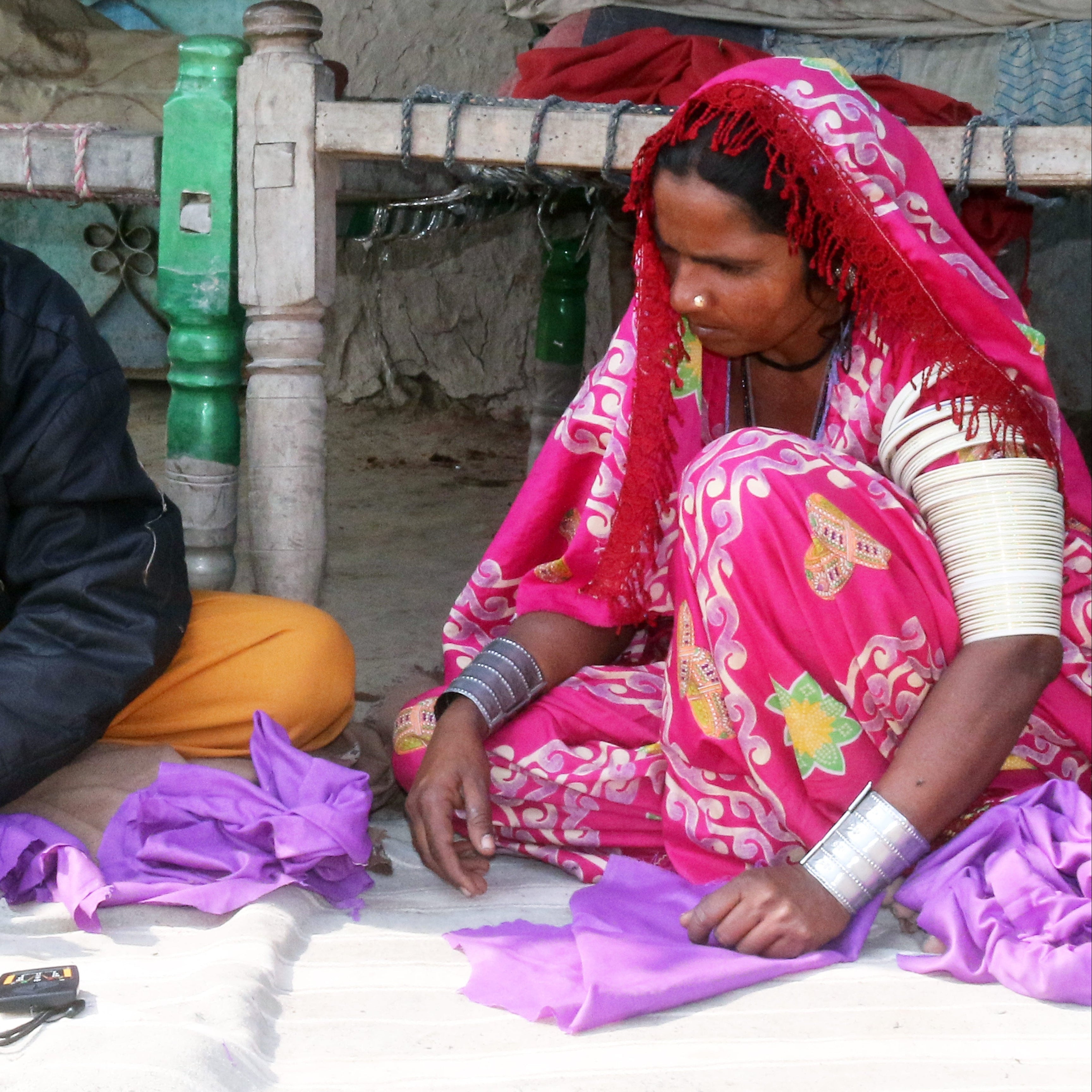 man and women sewing clothes sitting on ground