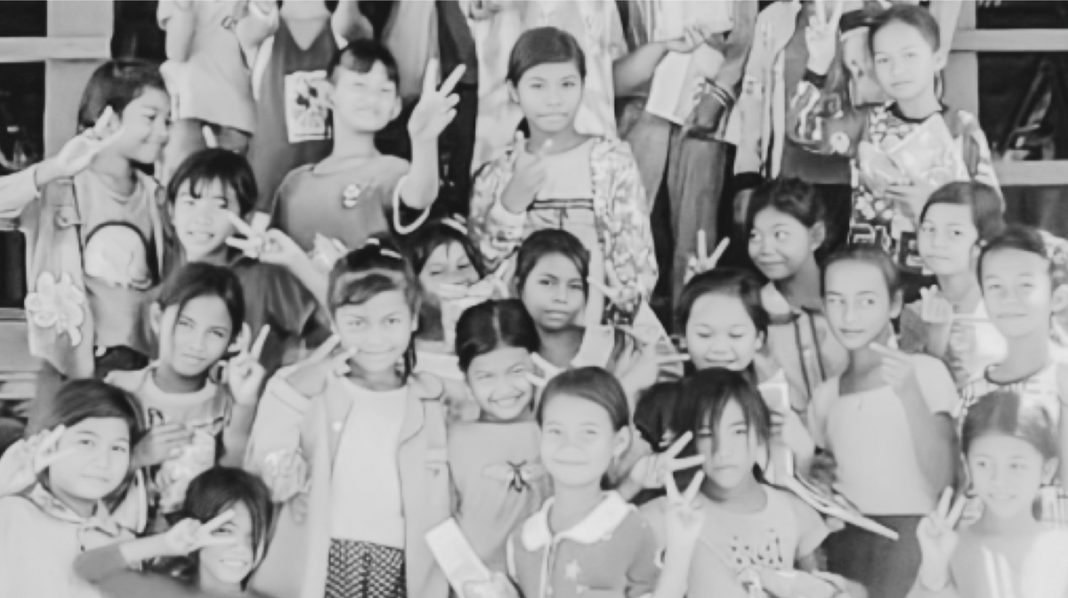 black and white photo of children smiling and making peace sign at camera